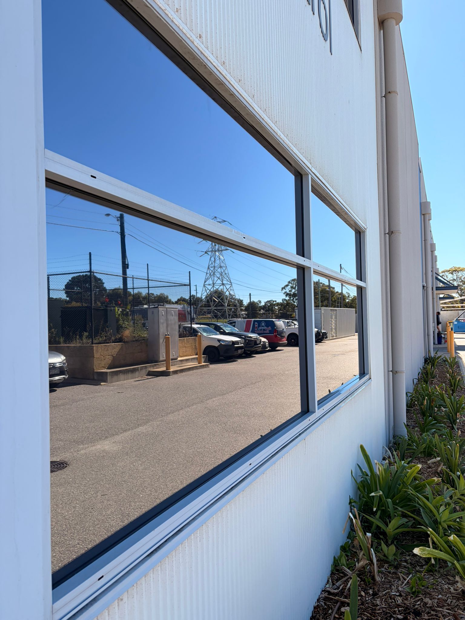 After commercial window cleaning O'Connor - large format window panel crystal clear reflecting car park and blue sky