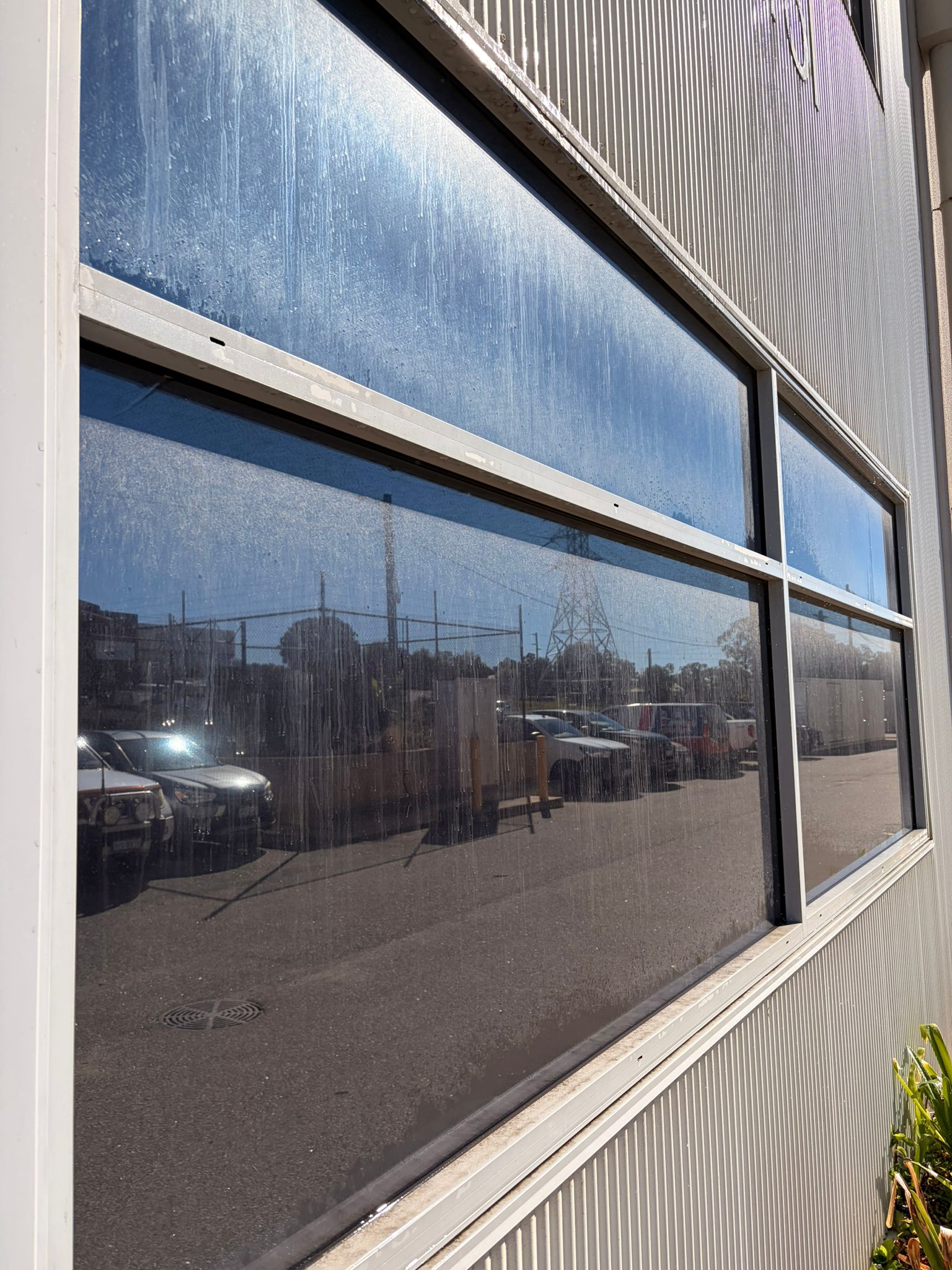Before commercial window cleaning O'Connor - heavy vertical mineral streaking across upper commercial window pane